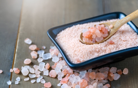 Pink Himalayan salt crystals in a rectangular dish with a wooden spoon